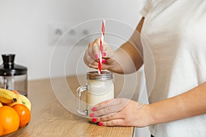 Woman Inserting a Straw into a Banana Smoothie Jar