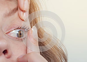 Woman inserts a contact lens into the eye. Close-up, domestic scene. Optics, Vision, Optical Instruments