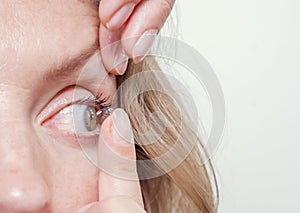 Woman inserts a contact lens into the eye