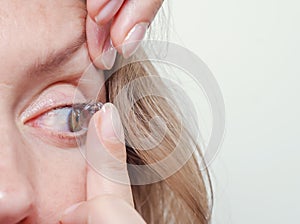 Woman inserts a contact lens into the eye