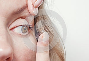 Woman inserts a contact lens into the eye