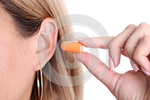 Woman inserts orange earplugs into ears, selection of silicone earplugs