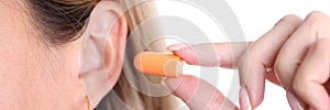 Woman inserts orange earplugs into ears, selection of silicone earplugs