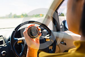 Woman inside a car and using compass to navigate while driving the car