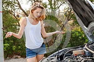 Woman inspecting her car engine after a breakdown