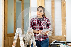 Woman inspecting rooms in building site, checking documents