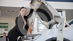 A woman inspecting under the hood of a car at the showroom
