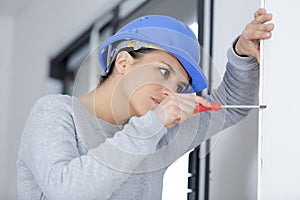 woman installing window handle with screwdriver photo