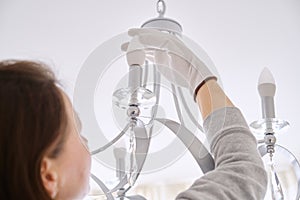 Woman installs LED lights in new ceiling chandelier