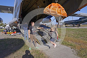 woman instructor teaching little girl how to handle parachute using flying landing simulator, airshow. Kyiv, Ukraine