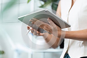 Digital Interaction and Technology. A woman holding a tablet, engaged in digital tasks with a stylus in a modern photo