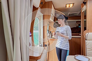 Woman in the interior of a camper RV motorhome with a cup of coffee looking at nature