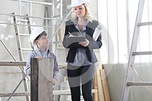 Woman interior designer or architect mom with her son at work, they choose how to furnish the house, inside the construction site