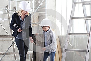 Woman interior designer or architect mom with her son at work, they choose how to furnish the house, inside the construction site