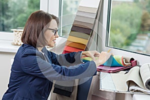 Woman interior designer, works with samples of fabrics for curtains and blinds.