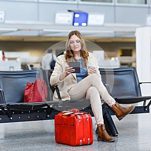 Woman at international airport, reading ebook and drinking coffe