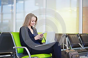 Woman in international airport terminal, checking her phone