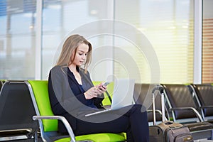 Woman in international airport terminal, checking her phone