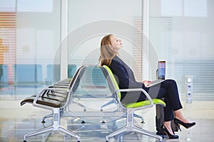 Woman in international airport terminal, working on her laptop