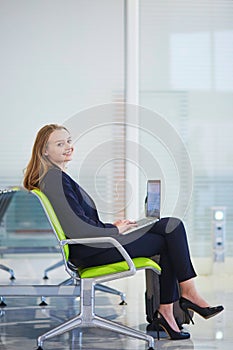 Woman in international airport terminal, working on her laptop