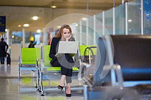 Woman in international airport terminal, working on her laptop