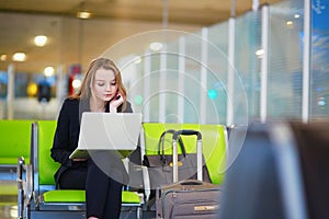 Woman in international airport terminal, working on her laptop