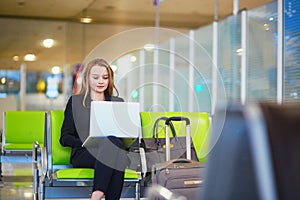 Woman in international airport terminal, working on her laptop