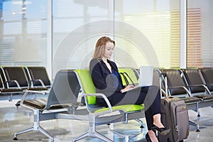 Woman in international airport terminal, working on her laptop