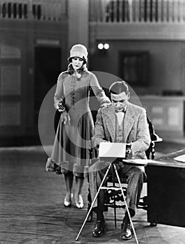 Woman interrupting man at typewriter