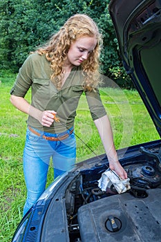 Woman investigates car oil level with dipstick