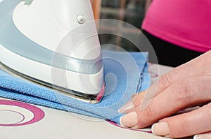 Woman ironing a blue dishcloth