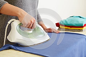 Woman ironing blue polo shirt