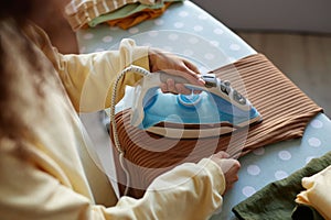 Woman Ironing Clothes with Light Blue Iron Appliance at Home