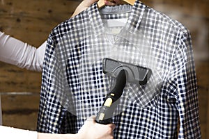 Woman ironing shirt with garment steamer