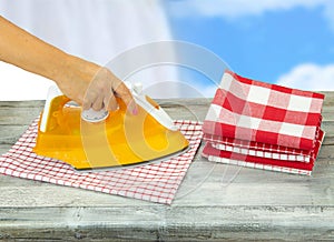 Woman ironing tablecloths on rustic grey table with a blue white photo