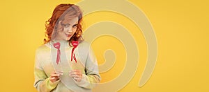 Woman isolated face portrait, banner with copy space. cheerful flirty redhead girl with red heart sticks on yellow