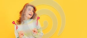 Woman isolated face portrait, banner with copy space. happy redhead girl with red heart sticks on yellow background