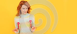 Woman isolated face portrait, banner with copy space. positive flirty redhead girl with red heart sticks on yellow