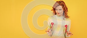 Woman isolated face portrait, banner with copy space. positive flirty redhead girl with red heart sticks on yellow