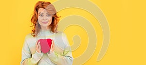 Woman isolated face portrait, banner with copy space. smiling redhead girl with red heart on yellow background.