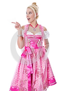 Woman isolated in a pink bavarian dirndl is pointing