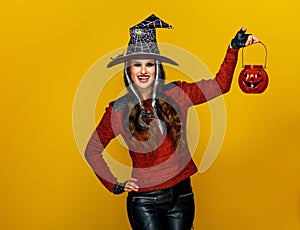 Woman isolated on yellow background holding jack-o-lantern