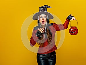 Woman isolated on yellow background holding jack-o-lantern