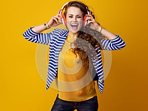 Woman isolated on yellow with headphones listening to music