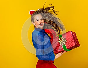 Woman isolated on yellow with red present box running