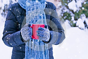 Woman in jacket and scarf outside holding warm drink