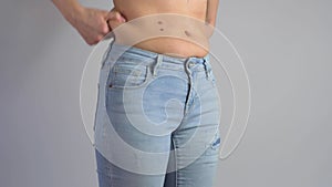 Woman in jeans holds her belly fat. Woman overweight pinch a fat on her abdomen