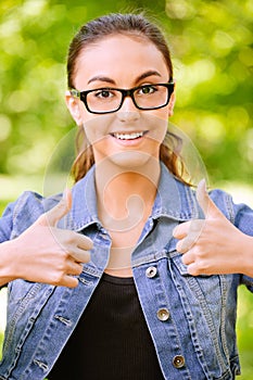 Woman in jeans jacket lifts thumbs