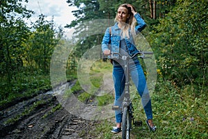 Woman in jeans riding on a bicycle at rural road