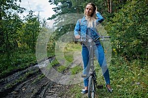 Woman in jeans riding on a bicycle at rural road